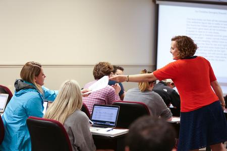 Janna Chance, associate professor of English, hands papers to a student during class.  - Photo by Kristi McMurry Woody