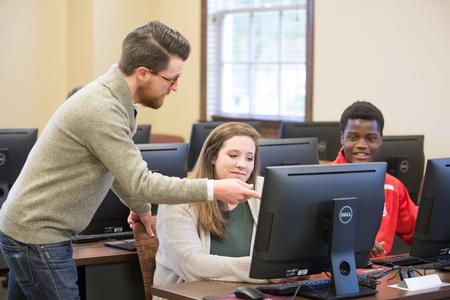 Aaron Beasley, visiting assistant professor of English, works with some students on an assignment after class.  - Photo by Kristi McMurry Woody