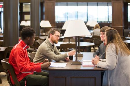 Aaron Beasley, visiting assistant professor of English, chats with some of his students in the library after class. - Photo by Kristi McMurry Woody