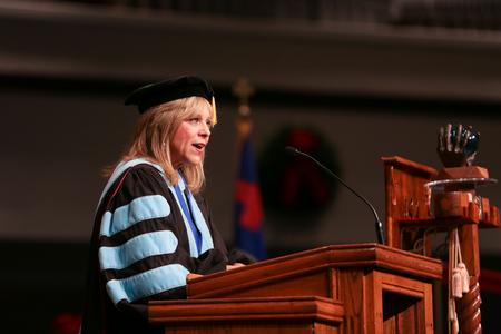 Beverly Absher, dean of the school of adult and professional studies, reads from Matthew during fall graduation. - Photo by Kristi McMurry Woody