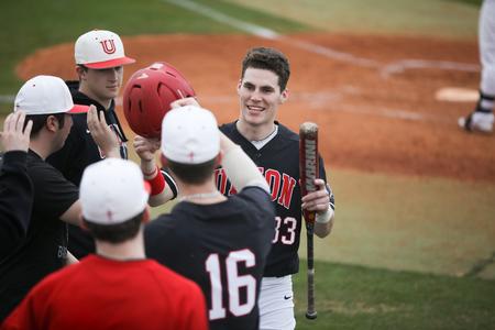 Bulldog baseball players celebrate with David Robins after he scored a run against Harding University. - Photo by Kristi McMurry Woody