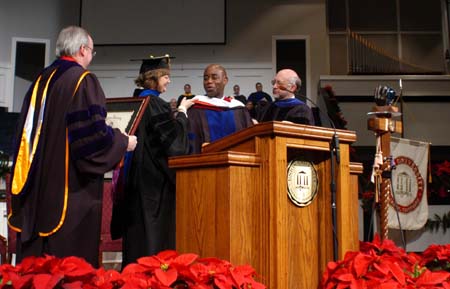 Provost Carla Sanderson and Dr. Richard Joiner placed a doctoral hood on Barry Black while he was receiving an honorary doctor of divinity degree during the fall graduation ceremony. - Photo by Morris Abernathy