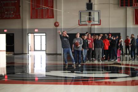 Riley Boggs, Christian ministry and missions major, attempts a half-court shot during the halftime of the Final Four game of the NCAA DII tournament. Students were able to watch a live stream of the game in the Fred Delay Gym. - Photo by Kristi McMurry Woody