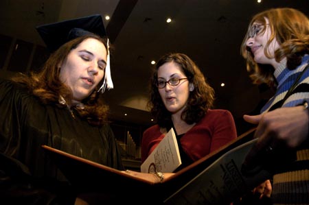 Journalism graduate Melinda Eckley of Gladwin, Mich. takes a look at her diploma with friends shortly after the fall graduation ceremony. - Photo by Kathleen Murray