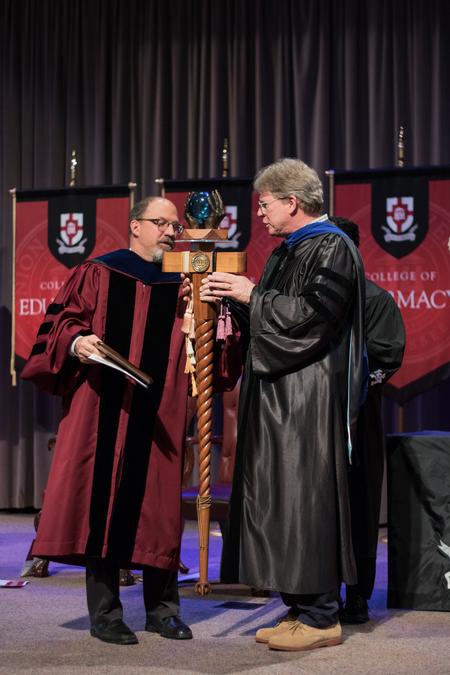 Scott Huelin, director of the honors community, hands off the mace to newly named Faculty Member of the Year Mark Bolyard, university professor of biology and department chair. - Photo by Janelle Vest
