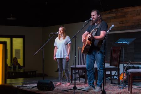 Emily Shoemaker, administrative assistant in University Ministries, and Nathan Shoemaker perform during Songs & Stories in Barefoots Joe.  - Photo by Lynn Tucker