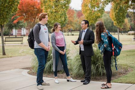 Students chat with Joseph Xu, assistant professor of marketing, outside The Logos. - Photo by Kristi McMurry Woody