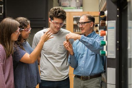 Michael Salazar, professor of chemistry, looks at some research with students in White Hall. - Photo by Kristi McMurry Woody