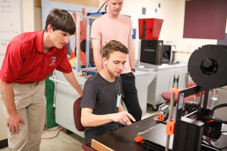 Georg Pingen, associate professor of engineering, helps get students set up with a 3D printer in the engineering department. - Photo by Kristi McMurry Woody