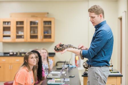 Jeremy Blaschke, assistant professor of biology, shows his class a ball python. - Photo by Kristi McMurry Woody