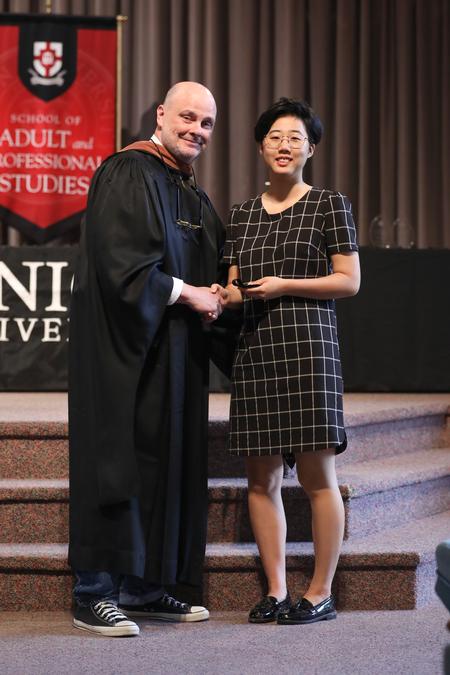 Lee Benson, university professor of art and department chair, presents the academic excellence medal in art to Yoo Lim Moon. - Photo by Kristi McMurry Woody