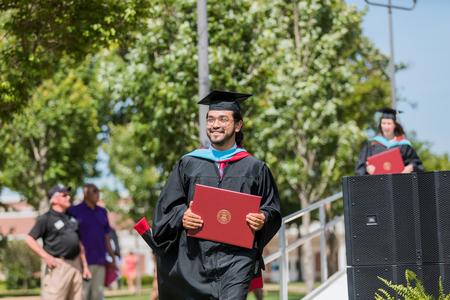 Graduates leave the stage with their diplomas at spring commencement. - Photo by Kristi McMurry Woody