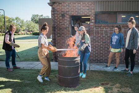 Paige Ward, instructional staff, supervises a raku firing with ceramics students in the art department. - Photo by Kristi McMurry Woody