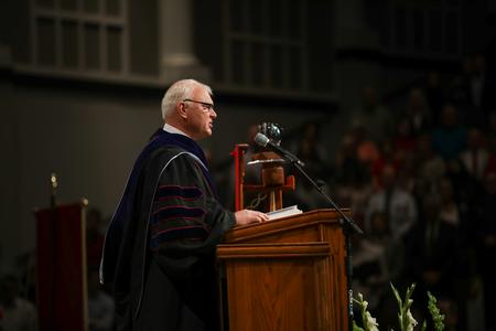 Mark Dubis, professor of biblical studies, reads scripture during the undergraduate ceremony of fall commencement.  - Photo by Kristi McMurry Woody