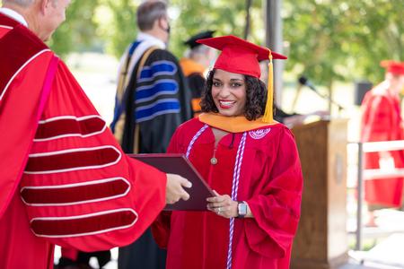 Gloria Michelle Paul Edacheril-Moore, doctor of nursing practice graduate, receives her diploma. - Photo by Kristi McMurry Woody