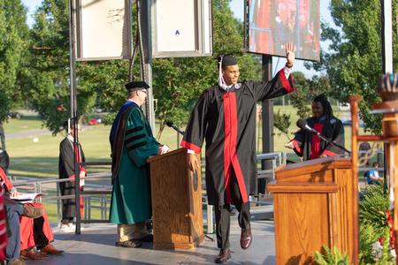 Samory Gueye, art graduate, waves at friends and family as he crosses the stage during Spring Commencement. - Photo by Kristi McMurry Woody