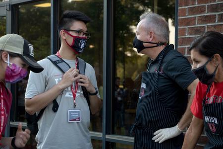 Raymond Chahyadi, economics with honors major, and Dub Oliver, president of the university, chat at the ice cream gathering for new students. - Photo by Joey Echeverria