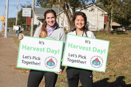 Students hold up signs for the community garden harvest day during Campus and Community Day. - Photo by Sarah Palmer Goff