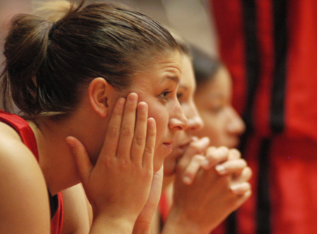 Freshman Merideth Richardson sits and watches the game from the sidelines.  Molly York and Tiffany Fisher do the same in the background. - Photo by Kristen Nicole Sayres