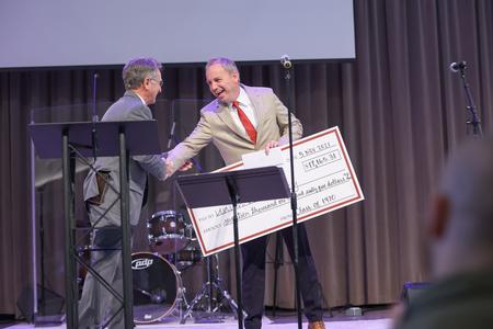 Bill Smith, class of 1970, presents Dub Oliver, president of the university, with a fundraising check from his class reunion during Homecoming chapel. - Photo by Kristi McMurry Woody