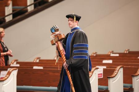 Jeremy Blaschke, associate professor of biology and faculty member of the year, carries the mace into fall graduation.  - Photo by Kristi McMurry Woody