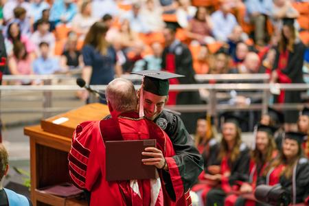 Lucas Brogdon, music graduate, receives his diploma and a hug from President Dub Oliver. - Photo by Kristi McMurry Woody