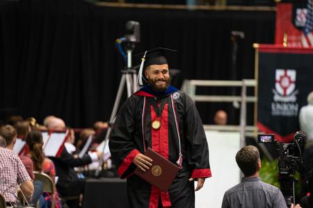 Nick Terra, philosophy graduate, smiles to his friends and family as he walks off the stage during spring graduation. - Photo by Kristi McMurry Woody