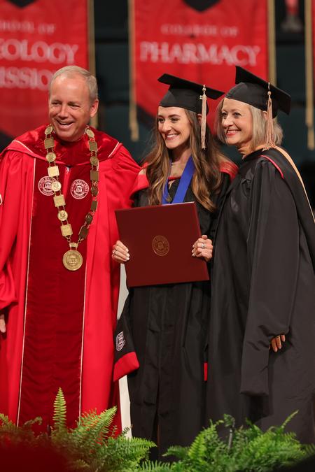 7/30/22 - Sarah Emery, MBA graduate, receives her diploma with President Dub Oliver, and her mom, Brooke Emery, associate dean for the McAfee School of Business. - Suzanne Rhodes