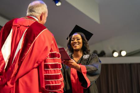 Kamaria Transor smiles as she receives her accounting degree from President Dub Oliver during the fall undergraduate commencement ceremony. - Photo by Kristi McMurry Woody
