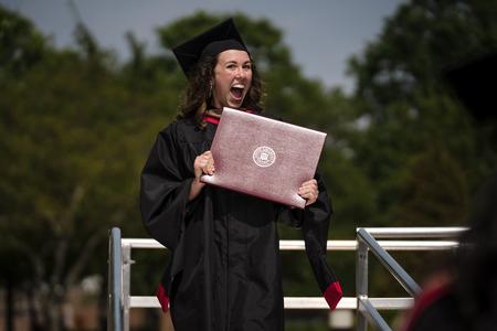 Delaney Sain, MBA graduate, flashes a smile after receiving her diploma at Spring Graduation.  - Photo by Kristi McMurry Woody