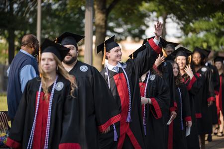 Matthew Harrell, a nursing major from Mount Juliet, Tenn., waves to friends and family as he and fellow classmates process into Spring Graduation. - Photo by Kristi McMurry Woody