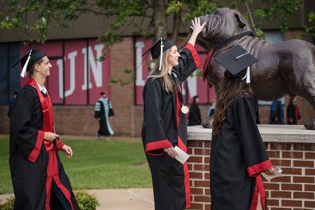Holly Bryan, applied linguistics and Spanish major, gives Buster a pat on her way to the Great Lawn for Spring Graduation. - Photo by Kristi McMurry Woody