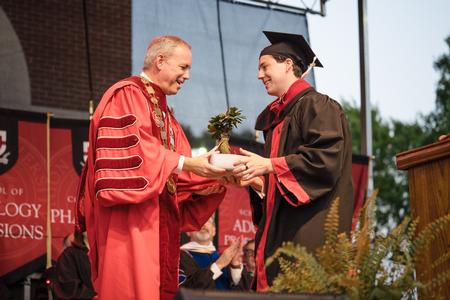Senior Class President Nicholas Bitterling presents President Oliver with a small tree to represent the Senior Class gift of refurbishment materials for the Union Trails. - Photo by Kristi McMurry Woody