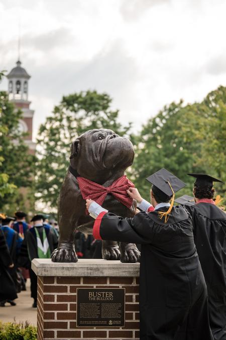 A considerate graduate straightens up Buster's bow tie on his way to the Great Lawn for Spring Graduation. - Photo by Kristi McMurry Woody