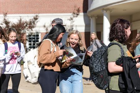 Abby Coleman and Ashtyn Delk admire the new Cardinal & Cream magazine as they wait in line for Amish donuts during Homecoming Week. - Photo by Karley Hathcock