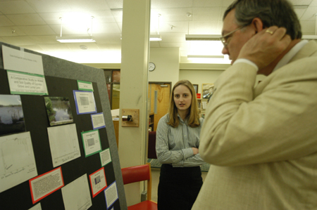 Senior Sarah Perlinger explains her chemistry research to Library Director Steve Baker who is looking over her poster presentation in the library during the scholarship symposium. - Photo by Kristen Nicole Sayres