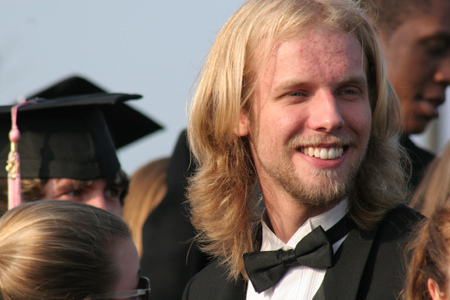 University Singer Aaron Powell flashes a smile as the singers assemble for the anthem during spring graduation. - Photo by Kyle Kurlick