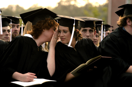Broadcasting graduate Susan Bacon whispers to political science graduate Kari Barnhart during the spring graduation ceremony. - Photo by Kathleen Murray