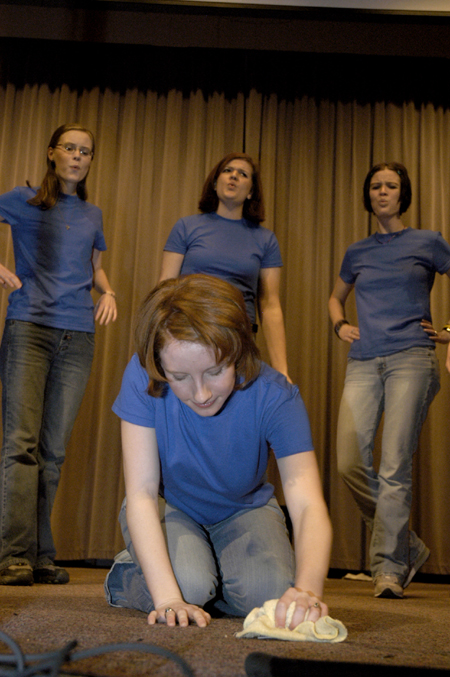 Senior Erin Hale washes the floor while Senior Laura Huggins, Sophomore Kelly Groover, Senior April Houston (back, left to right) whistle in the background during Sigma Alpha Iota's skit at Variety Show 2005.
 - Photo by Kathleen Murray
