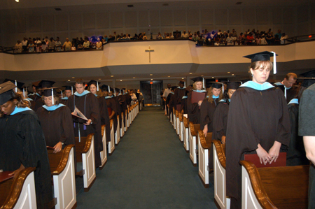 The summer graduates take time to give thanks for their accomplishments during the benediction.   - Photo by Morris Abernathy