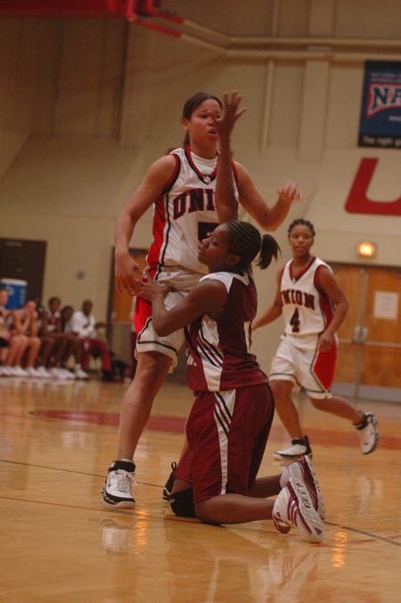 A Southern Nazarene player falls to the ground as she attempts to guard Union's Tiffany Fisher (14) while Jessica Graves (4) looks on. - Photo by Kristen Nicole Sayres