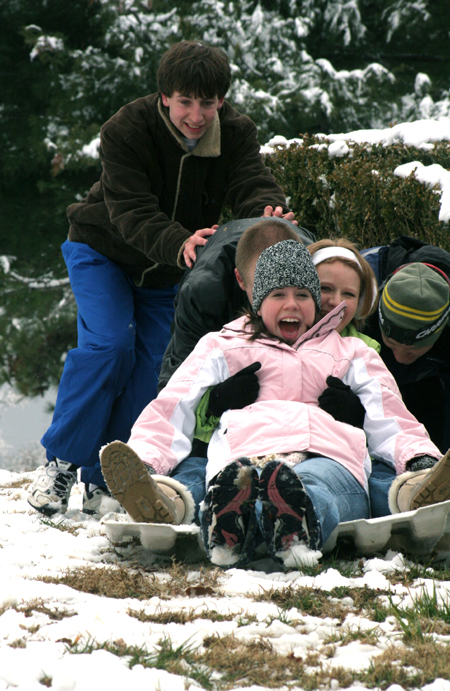 Cameron Armstrong, John Henson, and Brian Burns give Sarah Eastin and Brittany Sampson a little push while enjoying the snowy hill by the U. - Photo by Kyle Kurlick