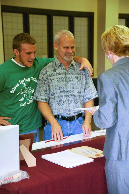 Freshman Josh Brubaker and his dad check-in with Residence Life Director Kathy Southall at Family Weekend 2002. - Photo by Lindsay Stavish