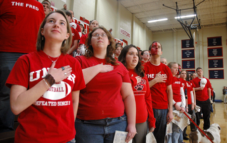 Students stand at attention during the National Anthem preceding a Lambuth game. - Photo by Brad Moore