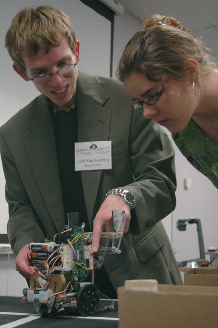 Junior Josh Shrewsberry shows Amber Roberts how sensors instruct the robot to pick up blocks and move them to boxes during the Union University Scholarship Symposium. - Photo by Kyle Kurlick