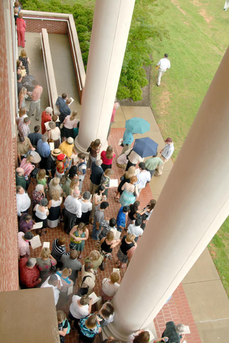 Scores of visitors sought refuge from a sudden rainstorm during graduation ceremonies on the Great Lawn. Many huddled under the columns at Jennings Hall. The rainstorm shortened the ceremony, but the awarding of degrees continued uninterrupted. - Photo by Tim Weisemann