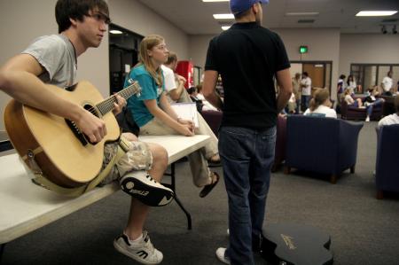 Jeffery Harper prepares and tunes his guitar before playing a couple of songs at the New Student Orientation open mic night. - Photo by Kyle Kurlick