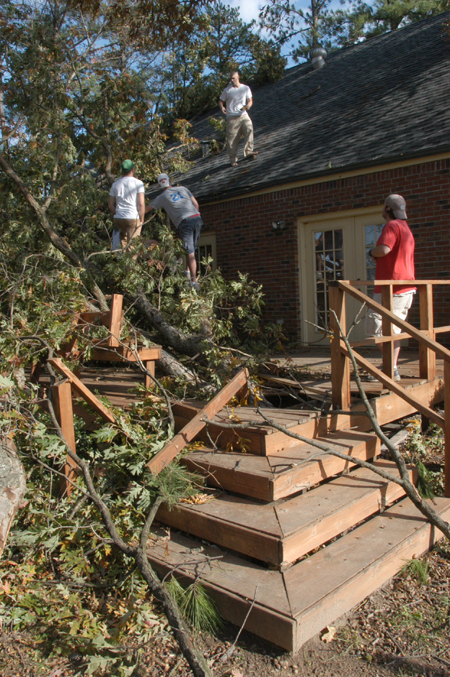 The SAEs worked on removing the large tree that fell on the back porch of their fraternity house on Saturday night as a result of the tornado. - Photo by Jim Veneman