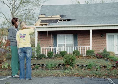 Senior Nicole Geyer, biology major, and junior Ashley Larue, public relations major, examine the damage done to the Kappa Delta house after the tornado. - Photo by Lindsay Stavish