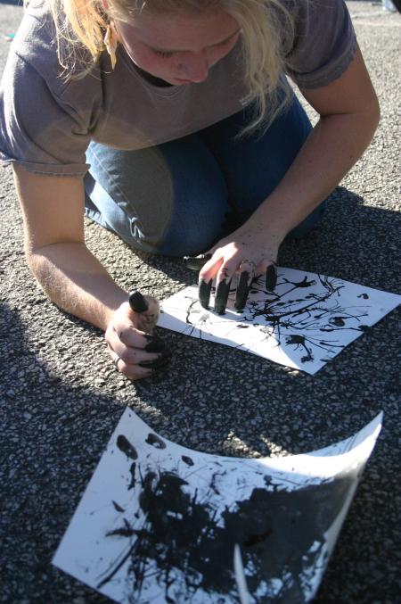 While on the art retreat, Freshman Abi Owen paints some paper outside as one of the projects with Tim Lowly, an artist from Chicago. - Photo by Stephanie Schroeder